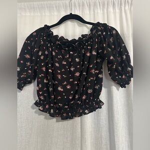 Express black floral off the shoulder crop top with ruffle details.